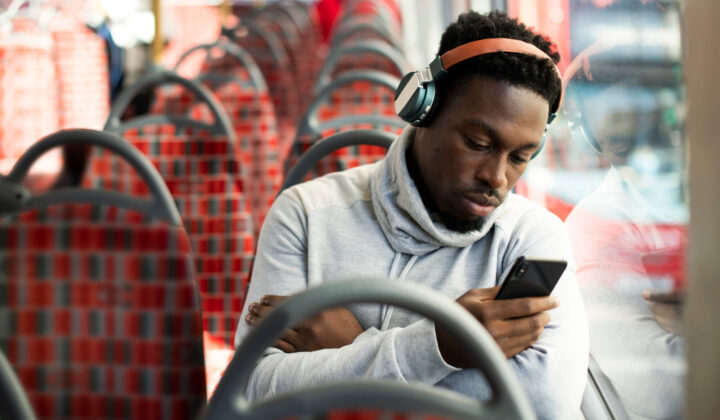 Man sitting on bus looks at his mobile phone