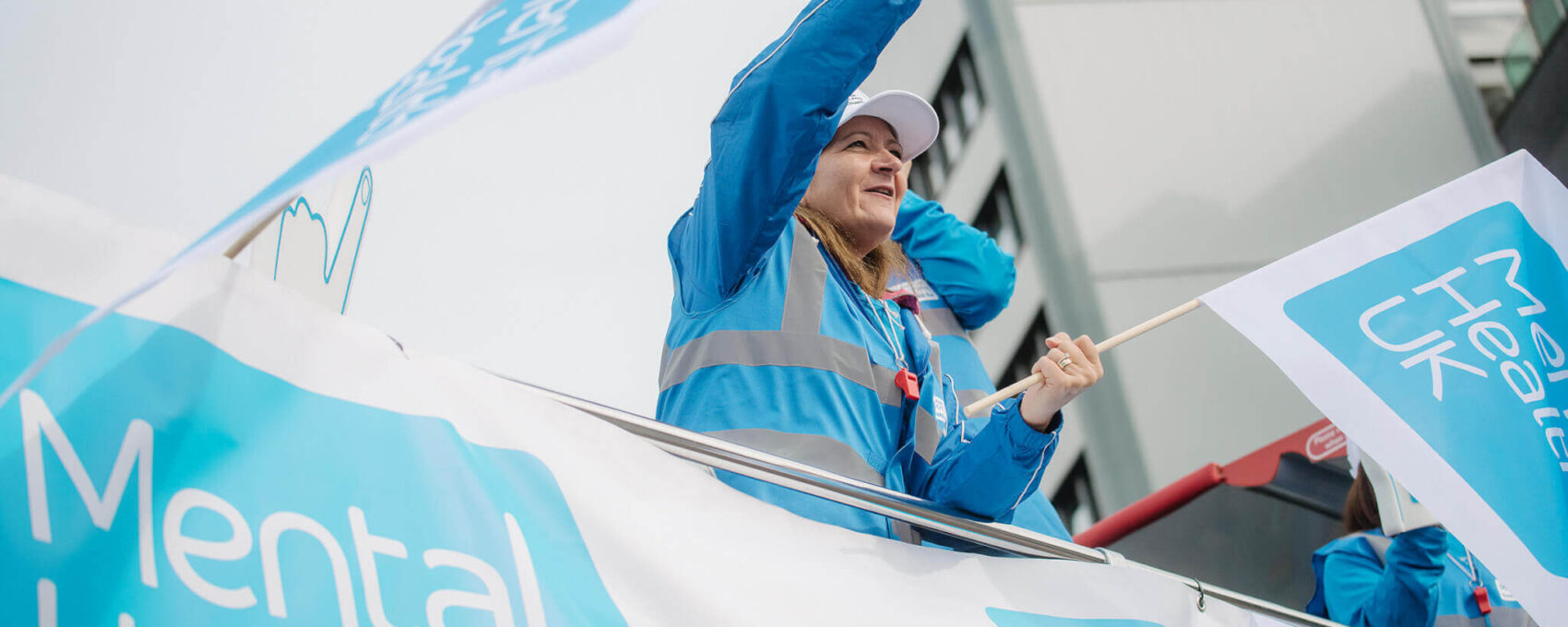 Mental Health UK charity supporters wave flags at event sidelines