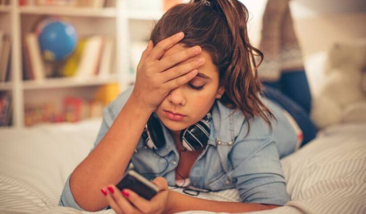Teenage girl with face in hand.