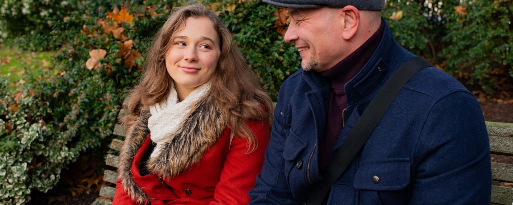 Father and daughter talking while sat on park bench
