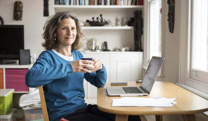 Woman drinking tea whilst looking at laptop