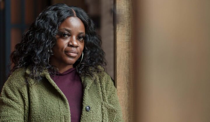 Lady in green jacket leans against window