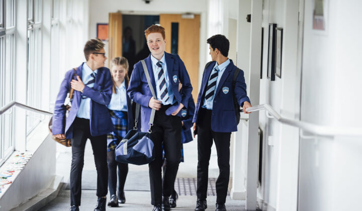 Small group of teenage school children walking through school corridor to their next class.