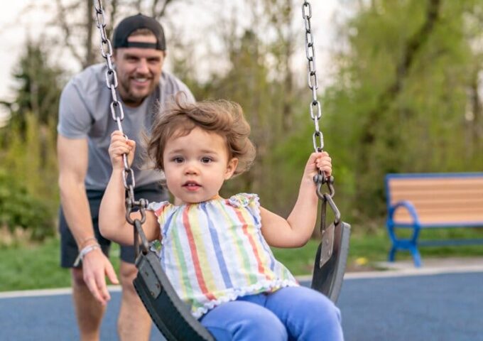 Dad pushing daughter on a swing