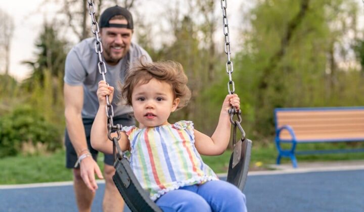 Dad pushing daughter on a swing