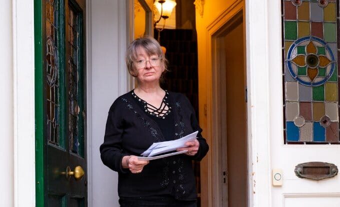 Female standing in the doorway with bill in her hand