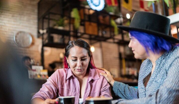Two friends having coffee and hand on shoulder to support