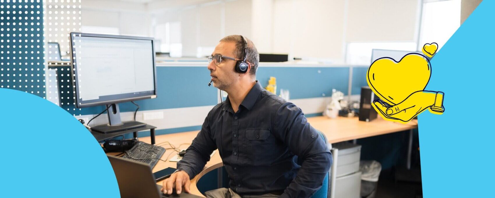 Man taking a call on his headset and looking at his laptop in an office