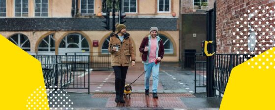 Two men walking along the street with their pet dog