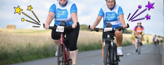 Two ladies riding bikes with MHUK T-shirts