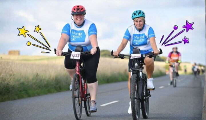 Two ladies riding bikes with MHUK T-shirts
